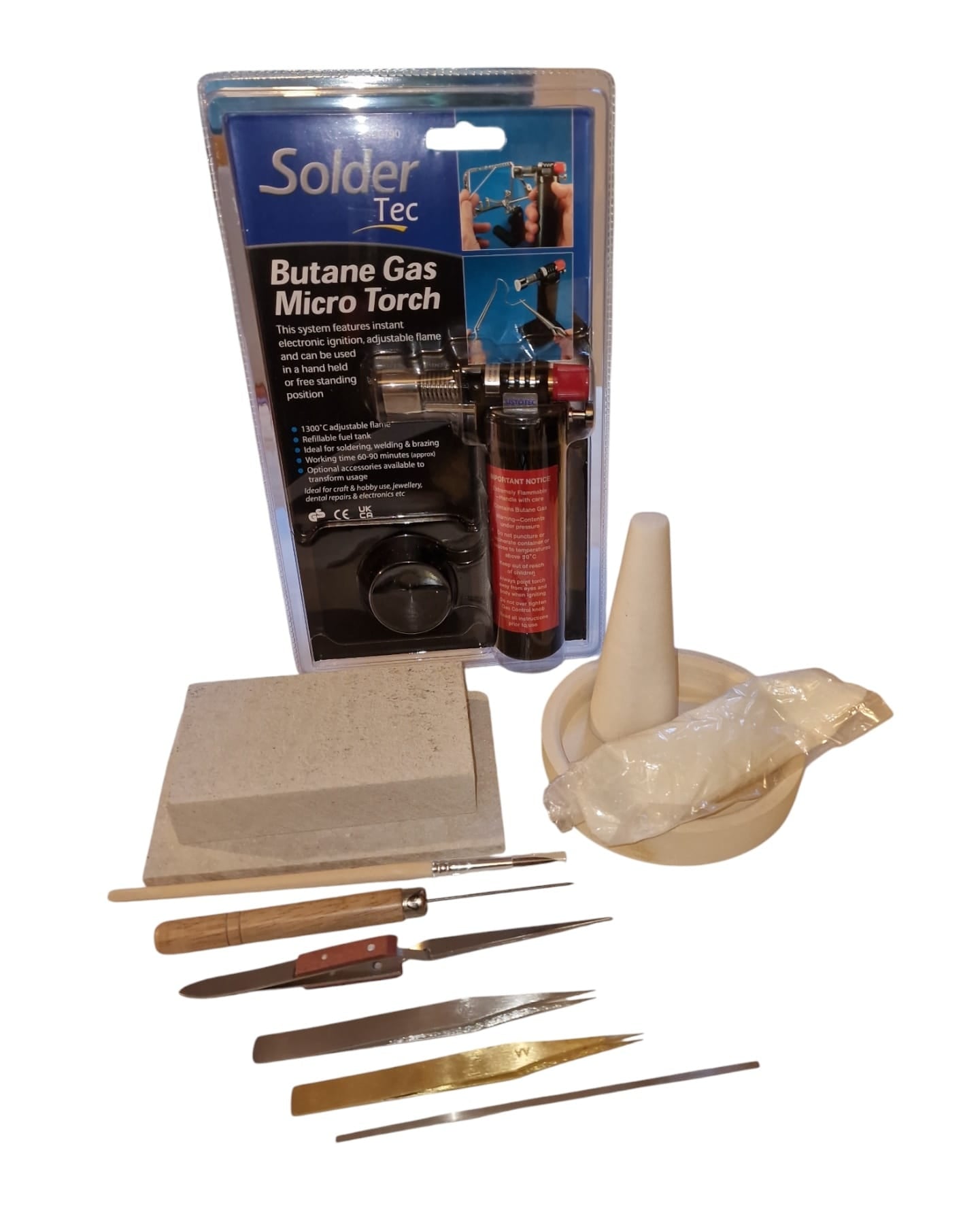 A collection of soldering tools including a butane soldering torch, soldering mat, soldering block, paintbrush, borax cone and tray, safety pickle, tweezers, and a solder probe.
