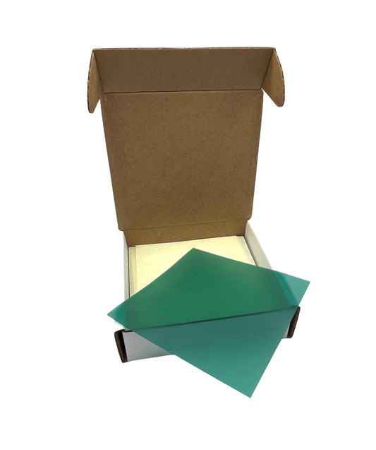Green jewellery wax sheets in assorted thicknesses, placed inside an open cardboard box. The sheets are translucent with a smooth texture.