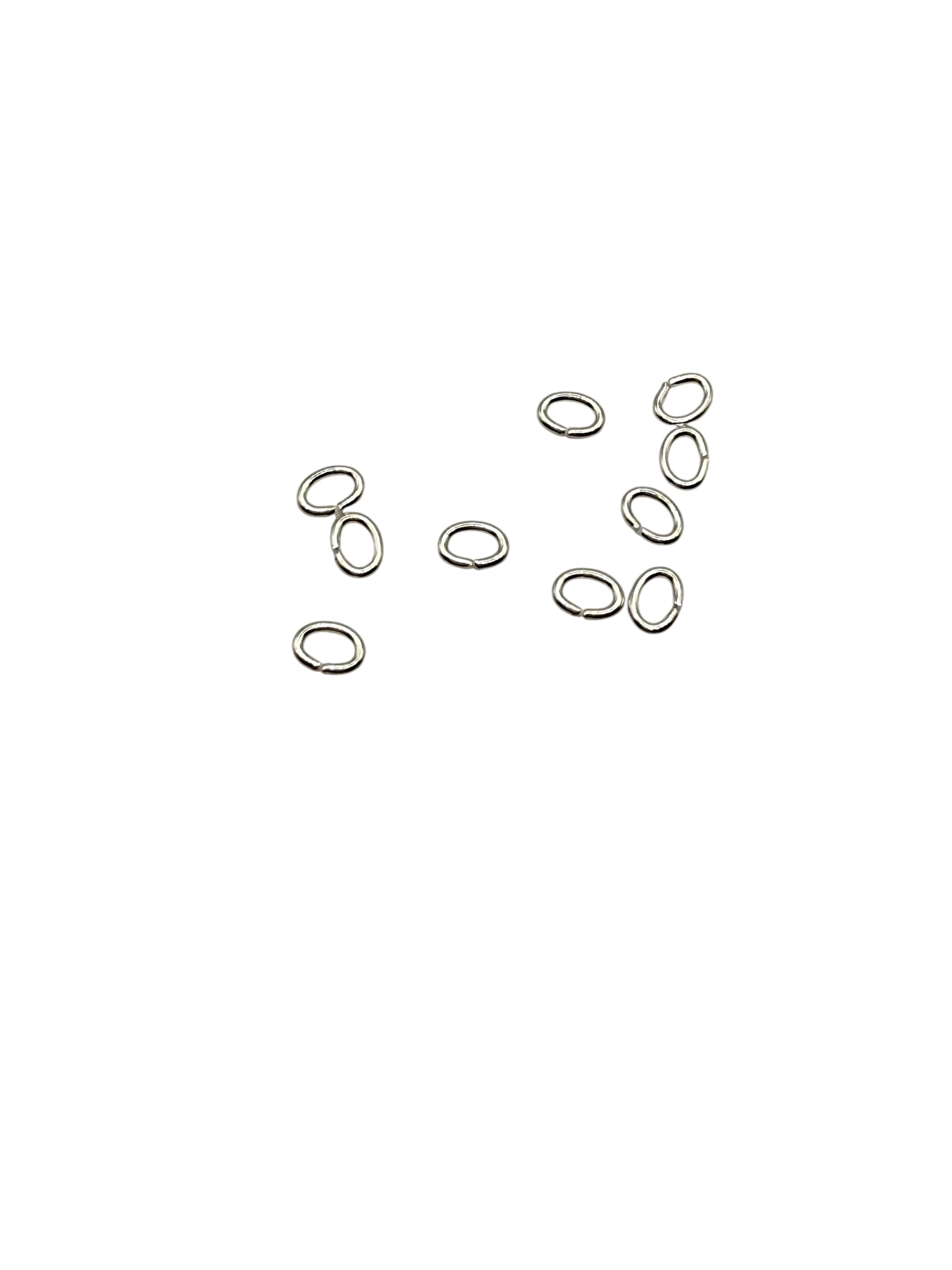 Silver oval jump rings scattered on a white background