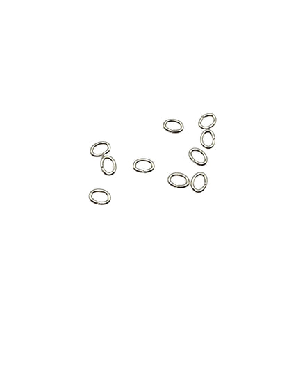 Silver oval jump rings scattered on a white background