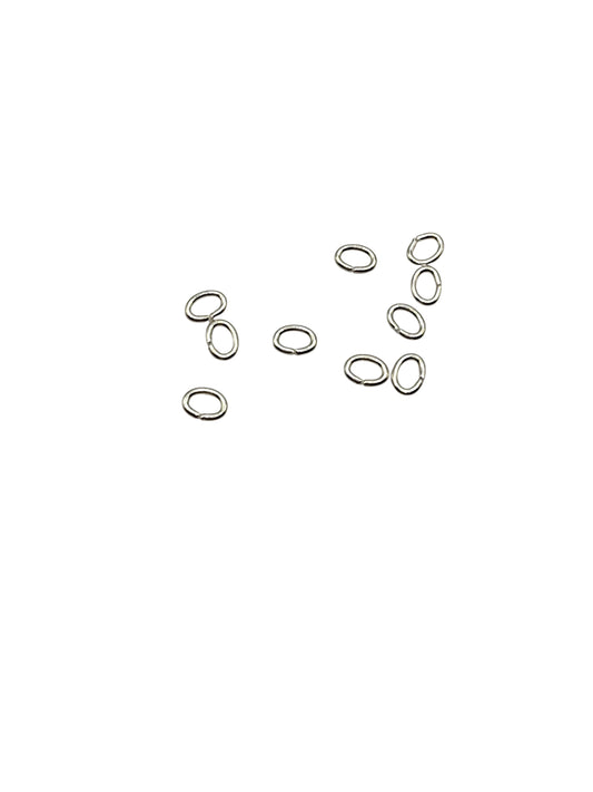 Silver oval jump rings scattered on a white background