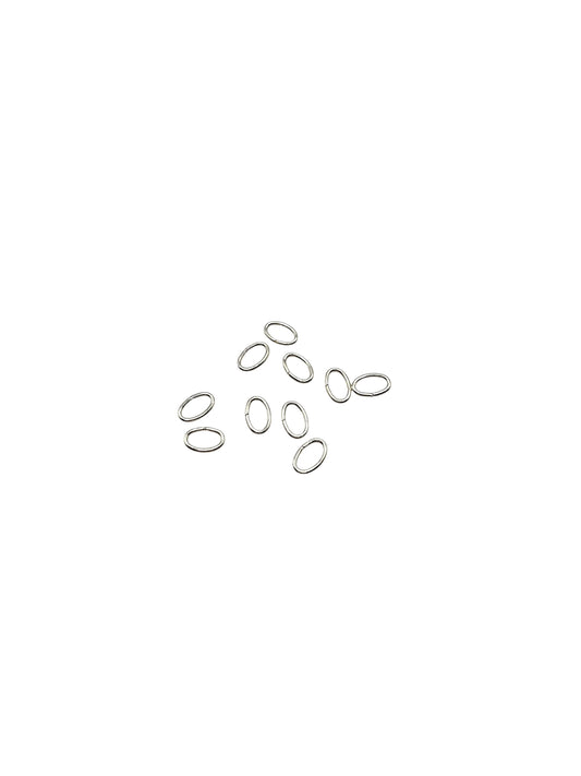 Silver jump rings scattered on a white background