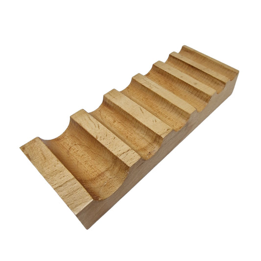 A well-polished, beige wooden swage block with semi-circular grooves used for metal bending.