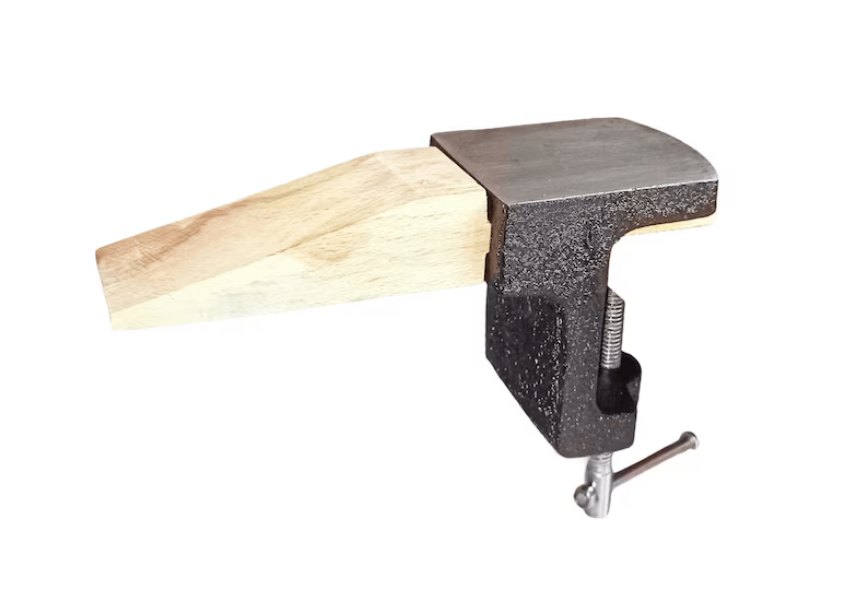 A metal anvil attached to a wooden bench peg with a G clamp, used for silversmith work or jeweler's bench tasks.