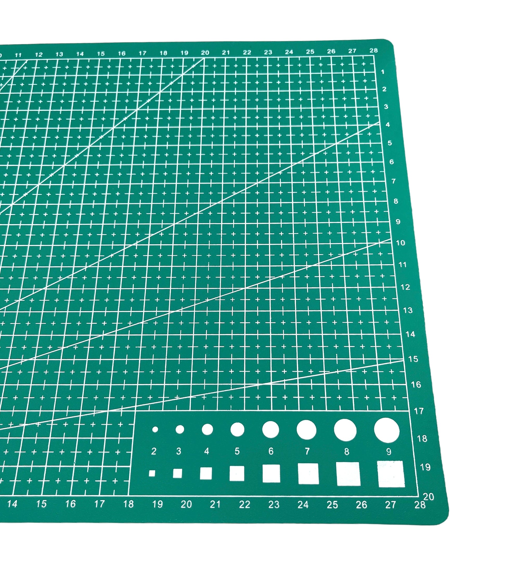 A green A4 cutting mat with grid lines and measurements marked for precision cutting - close up